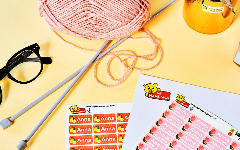 My Nametags iron on labels with a sewing needles and thread, on a yellow background