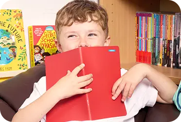 boy holding red notebook infront of his face