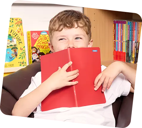 boy holding red notebook infront of his face